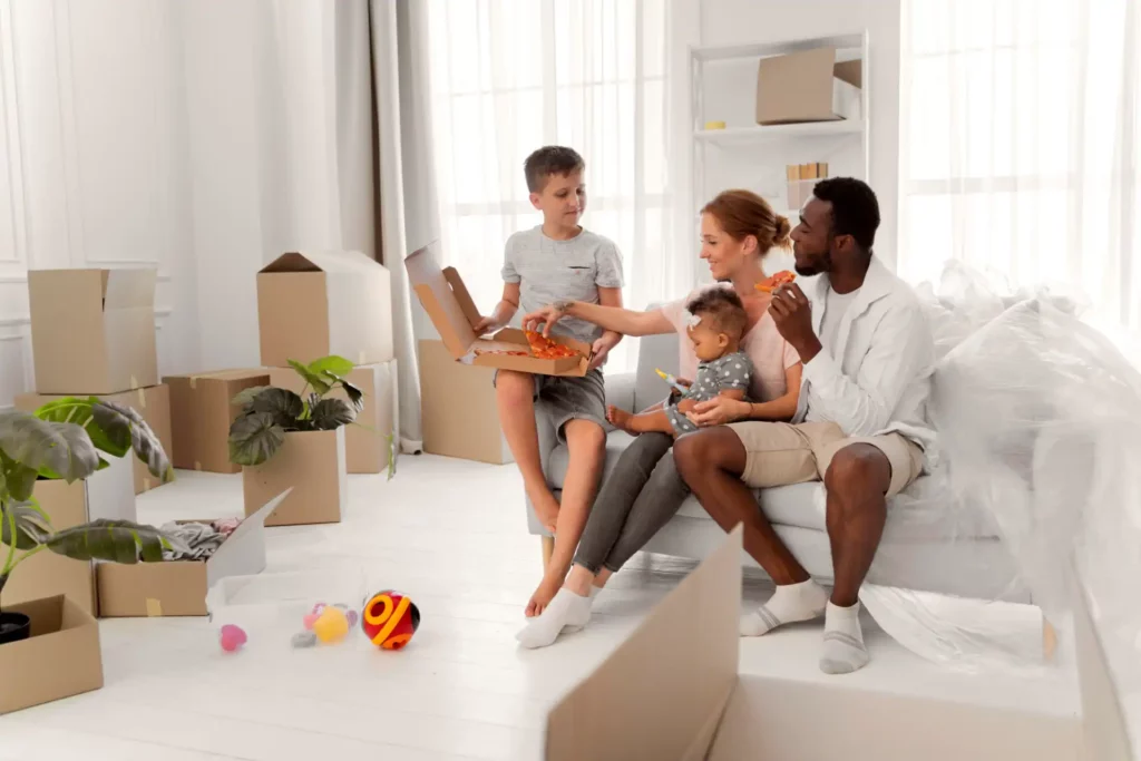 Família brincando e empacotando objetos na sala de estar durante a inscrição no Casa Paulista, com caixas de mudança e decoração moderna.
